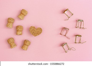 Creative layout with corks and muselets from champagne and heart on pink paper with copy space. Background for Birthday, party, wedding. Hen-party greeting card. 
