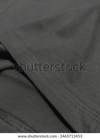 creative layout of dark ash grey plain basic t-shirt cotton material with stitching details zoom. flat lay, fashion and textile background detail