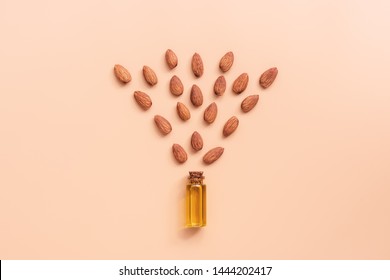 Creative Layout. Flat Lay Natural Almond Oil In A Bottle And Almonds On A Pastel Pink Background. The Concept Of Beauty And Health. Top View, Copy Space