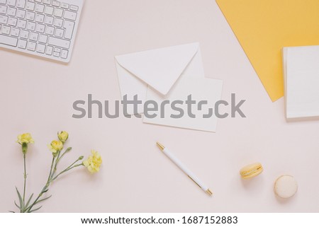 Creative layout with keyboard, paper blank, envelope, pen, flowers in vase, cookies. Office or home workspace.
