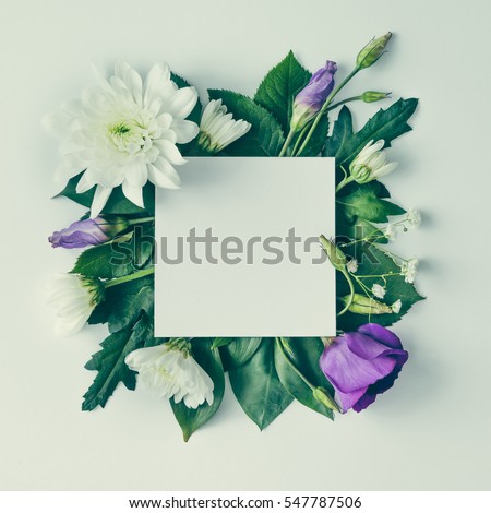 Creative layout made of flowers and leaves with paper card note. Flat lay. Nature concept