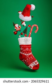 Creative layout made with flying Christmas socks, Santa Claus, pine tree and candy cane on green background. Minimal New Year season concept. Winter holidays idea.
