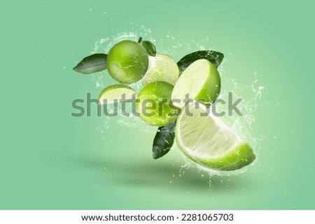Creative layout made form Lime fruit and Lime slices and water splashing on a green background.