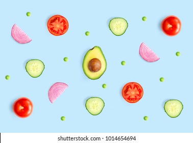 Creative layout made of green peas, avocado, tomato, onion and cucumber on the blue background.. Flat lay. Food concept.  