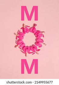 Creative layout for Mother's day made of two M letters and heart shaped pink flowers on pastel pink background. Minimal nature concept. Creative spring idea. Happy Mother's day. MOM letters. Flat lay.