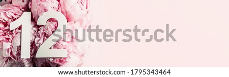 Creative layout. Peony flowers, digit twelve. Birthday greeting card with inscription 12. Anniversary concept. Top view. Copy space. Stylish white numeral on flower background. Numerical digit.