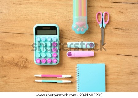 Creative layout with pink and turquoise school supplies, notebook, calculator on wooden background. Flat lay, top view. Back to school concept.