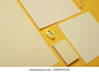 Creative layout of stationery, cards and sheets of paper on yellow background. Monochrome photography. Flat lay