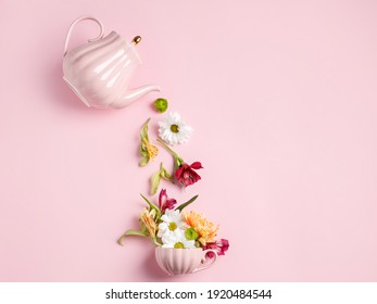 Creative layout with tea pot pouring fresh flowers and leaves into tea cup on pastel pink background. Creative floral spring bloom concept. Still life visual trend. Flat lay.