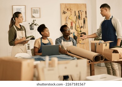 Creative leader, manager or boss talking to his design team in a modern studio or workshop. Male designer speaking to a group of colleagues and coworkers in a tailor, textile or fashion outfitter - Powered by Shutterstock