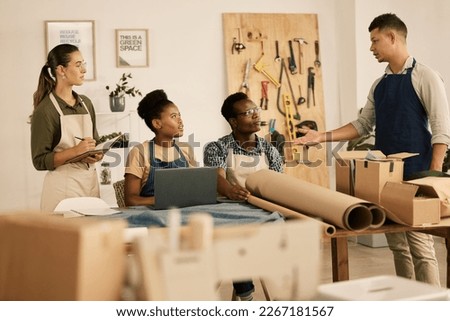 Creative leader, manager or boss talking to his design team in a modern studio or workshop. Male designer speaking to a group of colleagues and coworkers in a tailor, textile or fashion outfitter