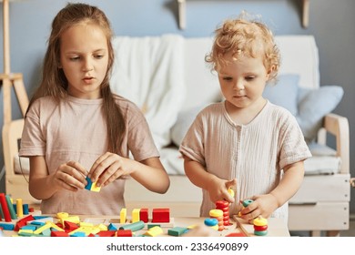 Creative learning game. Cognitive skill development. Montessori learning materials. Active playtime fun. Little girls playing with educational toys at home interior.