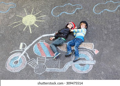 Creative leisure for children: two little funny friends in helmet having fun and motorcycle picture drawing and colorful chalks  Children  lifestyle  fun concept 