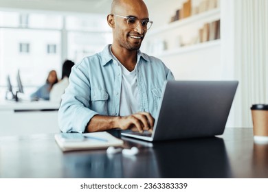 Creative male designer working on his laptop while sitting in an office. Young business man working on a new web design. - Powered by Shutterstock