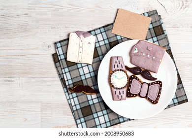 Creative male style gingerbread on a plate with blank paper card on light wooden table. International men's day or Father's Day concept. Cookies in the shape of a shirt, watch, bow tie and mustache. - Powered by Shutterstock