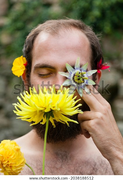 Creative\
man portrait with various flowers overlapped on a bearded white\
model face. Nature and sexual freedom\
concepts.