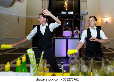 Creative master bartender mixologists juggling bottles and shakers at wedding reception