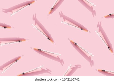 Creative medicinal pattern from syringes of pink background. Colorful concept of New Corona virus 2019-nCoV or COVID-19 vaccine. Flat lay, top view, copy space.