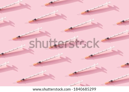 Creative medicinal pattern from syringes of pink background. Colorful concept of New Corona virus 2019-nCoV or COVID-19 vaccine. Flat lay, top view.