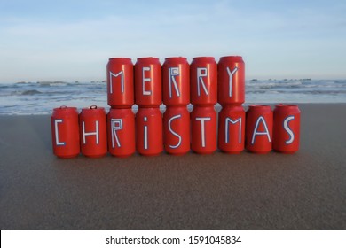 Creative Merry Christmas Message Painted On Colored Beer Cans With Beach Background