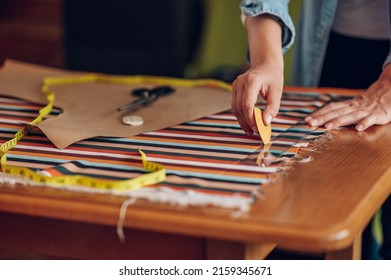 Une femme d'âge mûr créative crée un motif de papier avec des ciseaux pour coudre des vêtements. Femme couturière travaillant à la maison et taillant de belles robes artisanales. Concentrez-vous sur les tailleurs à la main en utilisant la craie