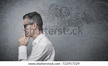 Creative mind at work: businessman thinking with hand on chin and gears mechanism, solution and problem solving concept