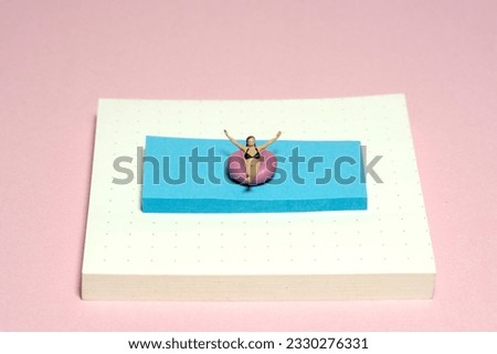 Creative miniature people toy figure photography. Sticky notes installation. A girl on a rubber tube boat chilling at swimming pool. Image photo