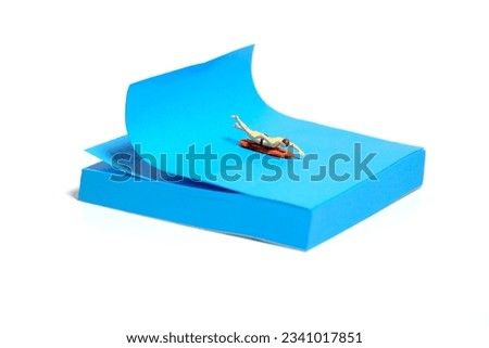 Creative miniature people toy figure photography. Sticky notes installation. A men surfer swimming above surfing board. Isolated on white background. Image photo