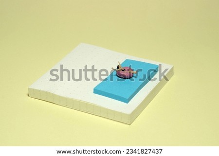 Creative miniature people toy figure photography. Sticky notes installation. A girl on a rubber tube boat chilling at swimming pool. Image photo