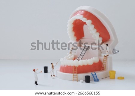 Creative miniature scene of tiny dentist figures cleaning and painting giant teeth on a dental model. Concept of oral hygiene, dental care, and health maintenance in a playful and artistic way.