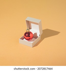 Creative and minimal New Year engagement concept with jewelry box and bright red Christmas bauble on sand coloured background. Trendy Vintage aesthetic. - Powered by Shutterstock