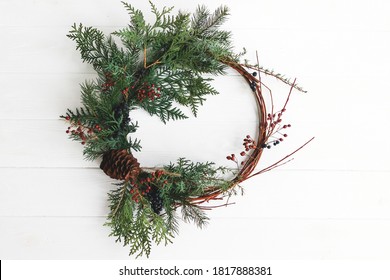 Creative modern christmas wreath with red berries and fir branches, isolated in white. Merry Christmas. Rustic christmas wreath hanging on white door, festive holiday decoration. - Powered by Shutterstock