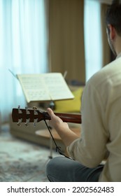 Creative Musician Play Acoustic Guitar Performing Music. Guitar Player Perform Melody Looking At Music Sheet, Rear View