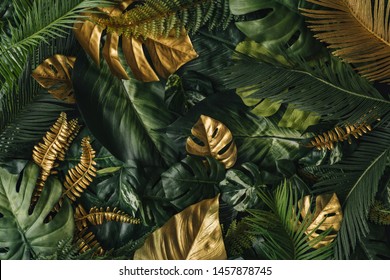 Creative nature background. Gold and green tropical palm leaves. Minimal summer abstract jungle or forest pattern.