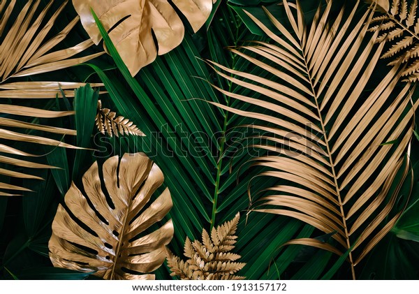 Creative nature background. Gold and green\
tropical Monstera and palm leaves. Minimal summer abstract jungle\
or forest pattern.