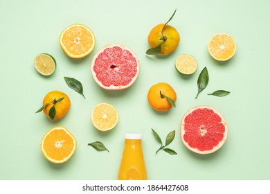 Creative neatly arranged food layout of fruits and leaves on pastel green background.  Flat lay juicy citrus fruits and bottle of freshly squeezed juice