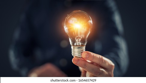 Creative new idea. Innovation, brainstorming, inspiration and solution concepts. The man is holding light bulb. Copy space background. - Shutterstock ID 1654657429