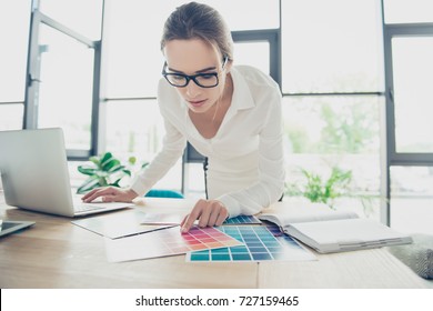 Creative occupation, making decision. Close up of female architect, in black trendy eyewear, whire formal outfit, choosing the colors for new project, looking at the pantone and pointing with finger