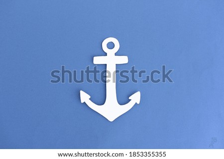Creative paper cutout of traditional anchor made of white paper on blue background
