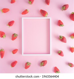 Creative pattern arrangement made of fresh strawberries on a vibrant pink background with white photo frame. Flat lay design.