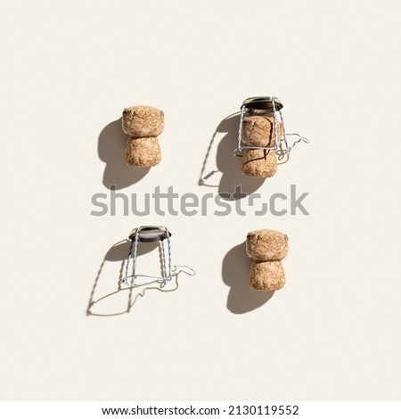 Creative pattern with champagne cork on beige background with hard light and shadows at sunlight. Minimal style layout with bottle cap from sparkling wine and metal wire muselet, top view, flat lay