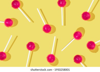 Creative pattern made with bold pink lolly pops on bright yellow background. Sweet happy life idea. Fun colorful concept with lolly pop.