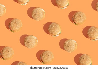 Creative Pattern Made Of Burgers On Bold Orange Background. Street Food And Fast Food Concept. Minimal Flat Lay Arrangement.