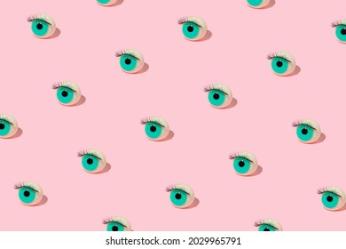 Creative pattern made with eyeball figurine with lash on pastel pink background. Halloween minimal creative concept. Blue eye retro fashion aesthetic idea.