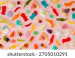 Creative pattern made of gummy candies on pastel pink background. Minimal trendy gummies concept. Jelly sweets aesthetic. Colorful flat lay background image. Top view.