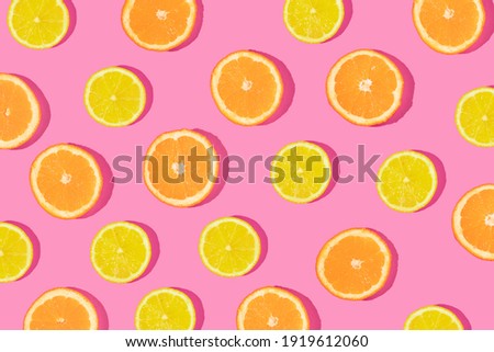 Creative pattern made with orange and lemon slices on bold pink background. Minimal flat lay. Spring or summer trendy concept. Fun idea with citrus fruits.