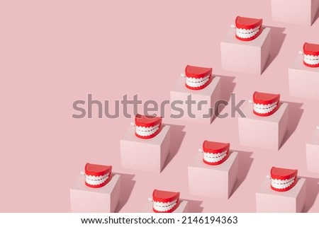 Creative pattern with teeth toy on pastel pink cube on pastel pink background. 80s or 90s retro fashion aesthetic concept. Minimal romantic smile idea.