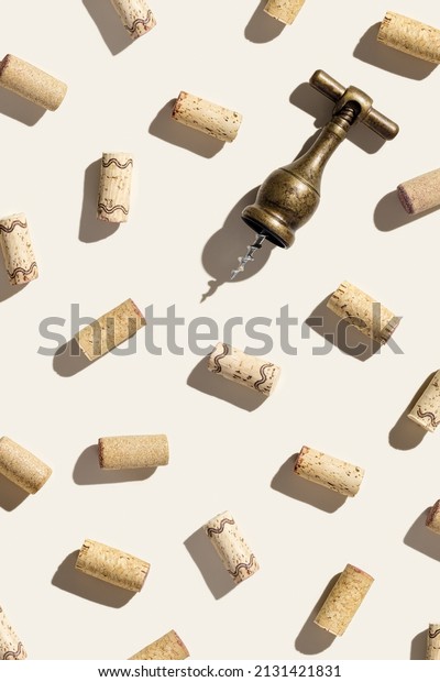 Creative pattern with wine corks and vintage\
corkscrew on beige background with shadows at sunlight. Minimal\
style layout with bottle cap, old bottle screw, design concept for\
wine list, top view