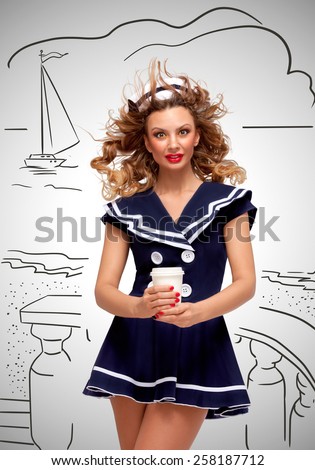Creative photo of a beautiful pin-up sailor girl with a coffee-to-go cup, having wind in her hair on grey sketchy background.