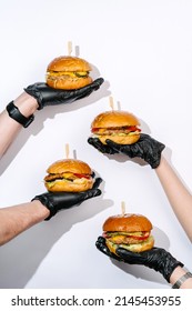 Creative photography of juicy burgers in hands on white background - Shutterstock ID 2145453955